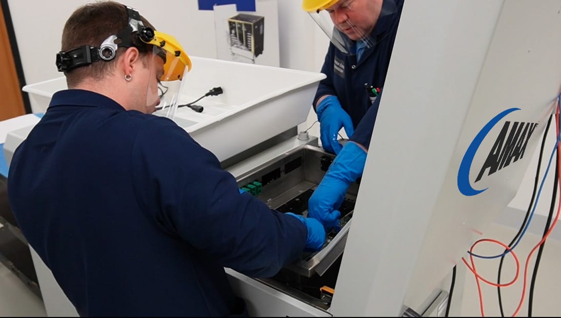 Technicians inspecting an immersion cooling tank for computer systems with visible AMAX branding.