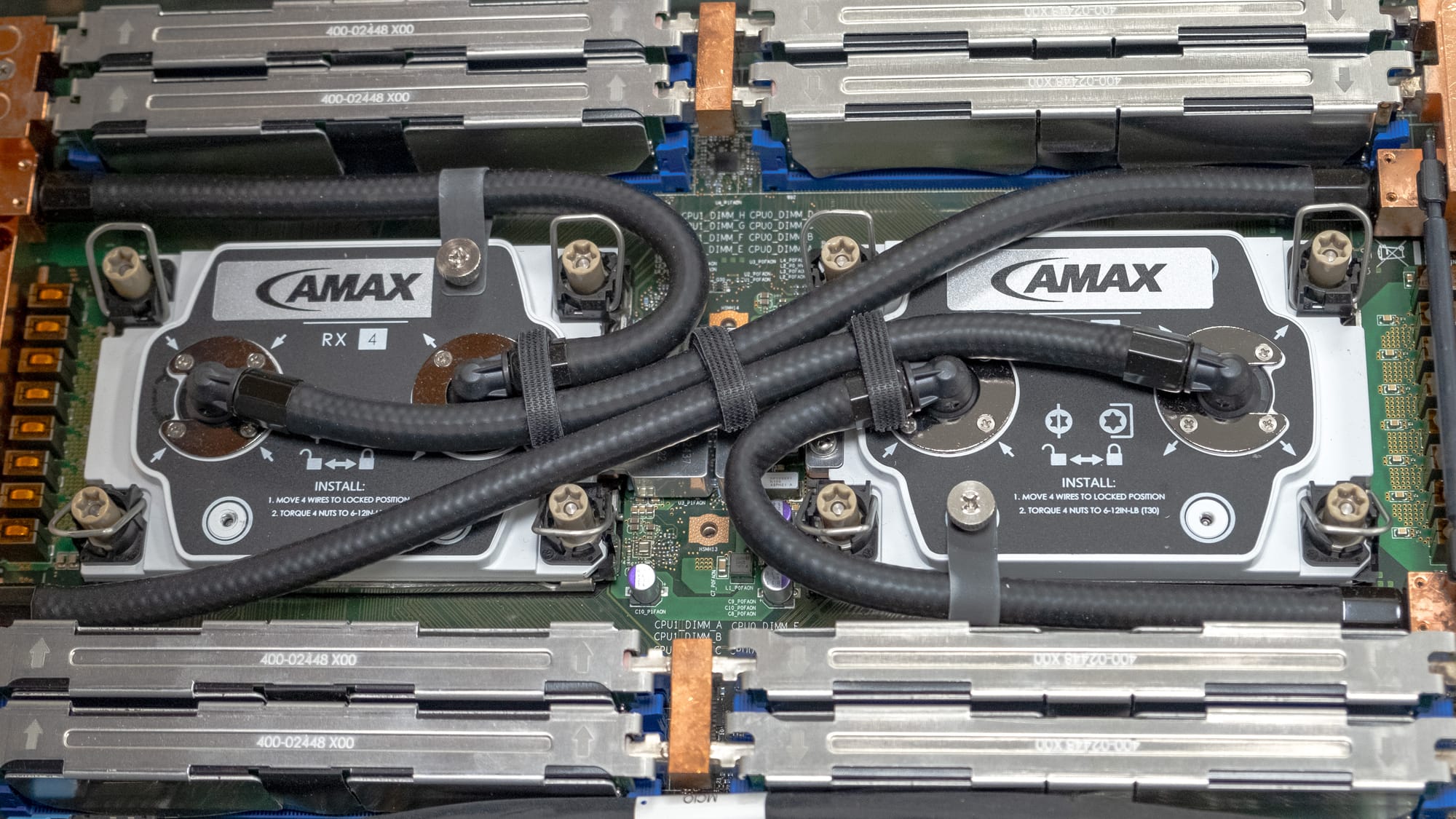 Close-up of a server's internal hardware featuring dual AMAX liquid cooling systems atop CPUs, surrounded by RAM modules and power cables.